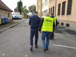 Zatrzymany mężczyzna prowadzony przez policjantów.