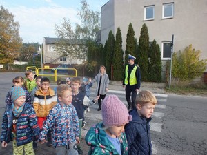 Policjantka przeprowadza dzieci przez jezdnię na przejściu dla pieszych