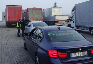 Nieoznakowane policyjne bmw stoi na pierwszym planie dalej policjanci prowadzą kontrolę