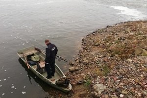 Policjant na zabezpieczonej łodzi kłusownika i z jego sprzętem wędkarskim