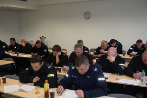 policjanci siedzą w ławkach na sali konferencyjnej