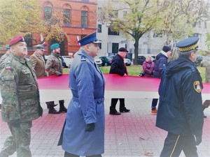 Komendant KMP we Włocławku niesie flagę Polski.