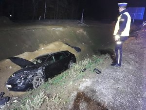 Policjant patrzący na jedno z rozbitych aut w przydrożnym rowie.