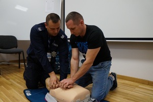 policjant uczy mężczyznę masażu serca
