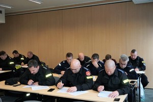 policjanci siedzą w ławkach na sali konferencyjnej