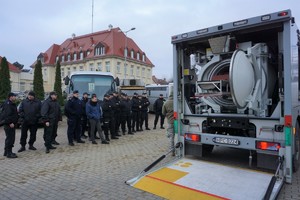 policjanci stoją przed wozem minerskim