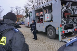 policjanci stoją przed wozem minerskim