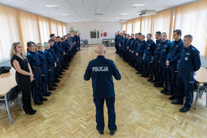 Policjant stoi przed policjantami ustawionymi w dwóch rzędach