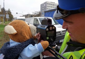 policjant dokonuje pomiaru prędkości z pluszowym misiem przyłożonym do urządzenia