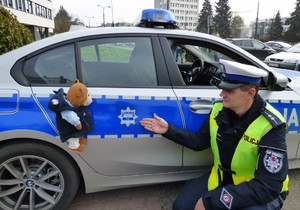 policjant wskazuje nr 112 pluszowemu misiowi