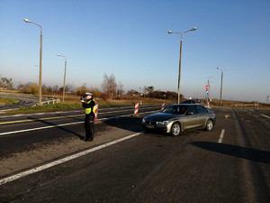 Policjant mierzy prędkość rejestratorem, a obok stoi nieoznakowane bmw