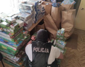 policjant kuca przy stosie zabawek