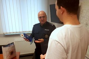 policjant przekazuje nagrodę mężczyźnie