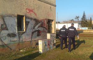 Policyjny patrol zmierza do wejścia opuszczonego budynku