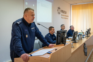 Komendant przemawia do policjantów siedzących przy ławkach