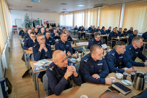 policjanci siedzą w ławkach na sali konferencyjnej