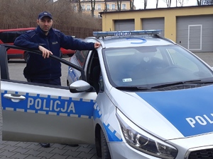 Policjant, który pomógł rodzinie stoi przy radiowozie