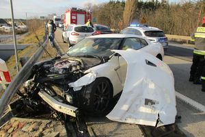 Zniszczone auto sprawcy zdarzenia, w tle strażacy i policjanci