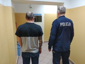 Policjant stoi na korytarzu z zatrzymanym