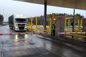 Ciężarówka podjeżdża pod bramkę autostradową, gdzie stoi policjantka z alco-blow