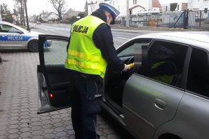 Policjant RD podaje kierowcy alco blow, w tle stoi radiowóz