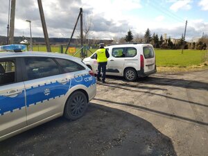 Policjant podchodzi do kierowcy białego auta dostawczego