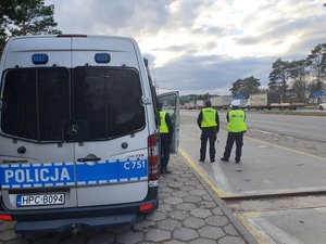 Trzej policjanci z patrolu stoją przy radiowozie