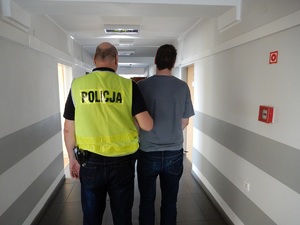 Policjant prowadzi zatrzymanego mężczyznę