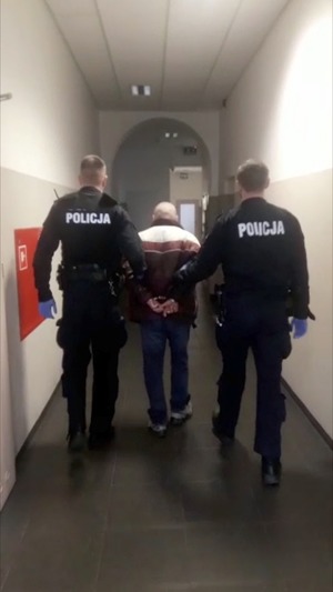 Policjanci prowadzą zatrzymanego mężczyznę