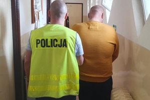 Policjant prowadzi zatrzymanego mężczyznę