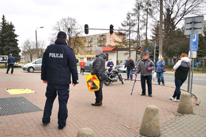 Policjant kontroluje osoby gromadzące się przy markecie