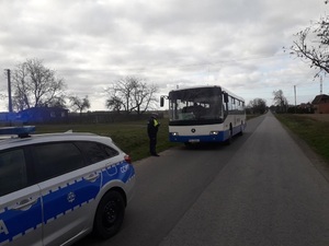 Kontrola autobusu. Przy nim stoi policjant, a przed nim zaparkowany radiowóz.