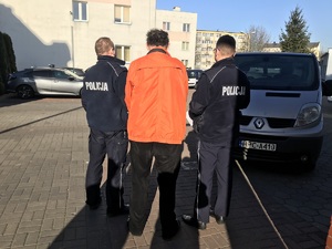 Policjanci prowadzą zatrzymanego mężczyznę