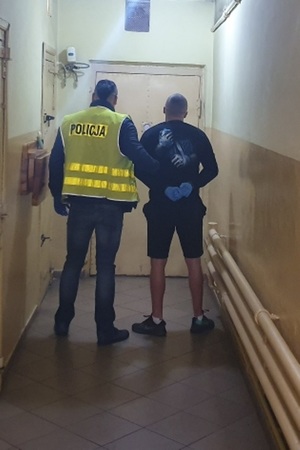 Policjant prowadzi zatrzymanego mężczyznę