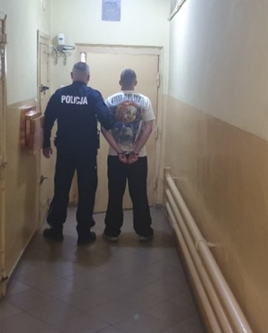 Policjant prowadzi zatrzymanego mężczyznę