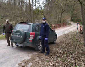 patrol podczas służby. Funkcjonariusze stoją przy aucie. W tle las.