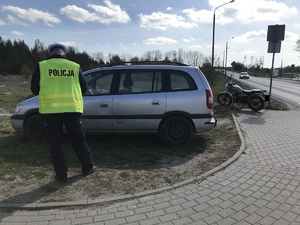 Policjant stoi przy zaparkowanym samochodzie