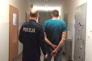 Policjant prowadzi trzeciego zatrzymanego.