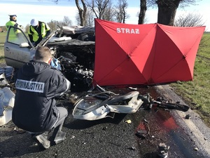 Technik kryminalistyki podczas oględzin pojazdu na miejscu zdarzenia.