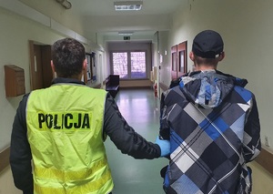 Policjant prowadzi zatrzymanego mężczyznę