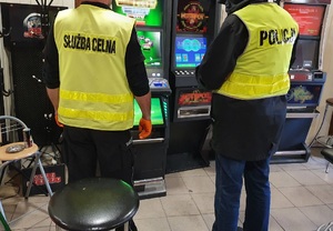policjant i funkcjonariusz KAS-u stoją przed maszynami do gier