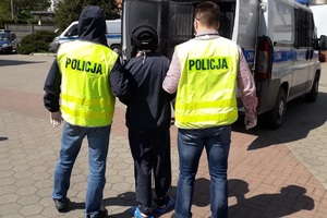 Policjanci prowadzą zatrzymanego mężczyznę