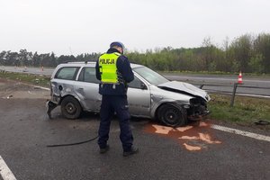 Policjant stoi nad rozbitym samochodem