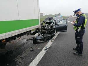 Policjant stoi nad rozbitymi samochodami i sporządza dokumentację