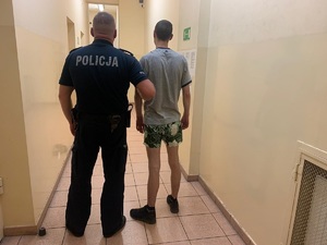 Policjant prowadzi zatrzymanego.