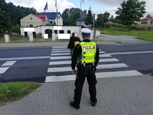 Policjant RD monitoruje przejście dla pieszych przez, które przechodzi rowerzystka