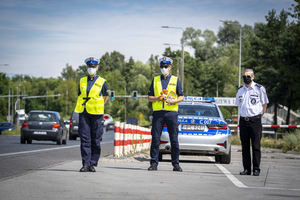 Policjanci i kapelan policji pozują do zdjęcia na tle radiowozu