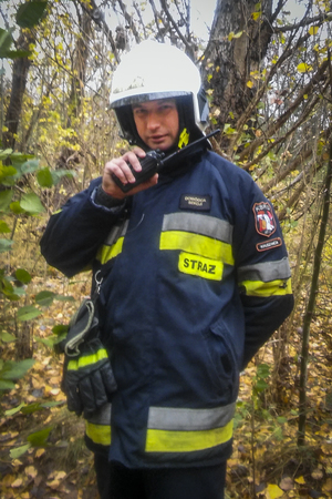 strażak pozuje do zdjęcia trzymając radiostację nasobną