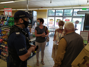 Policjanci i pracownicy Sanepidu rozmawiają z właścicielem sklepu
