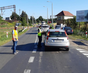 Policjantka kontroluje kierowcę stojącego przed przejazdem